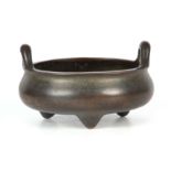 AN EARLY CHINESE BRONZE CENSER of squat bulbous form with loop handles raised on tapered feet,