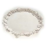A GEORGE III SILVER SALVER with raised shell work border and raised on scrolled hoof foot 16.5cm