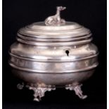 A CONTINENTAL SILVER OVAL TEA CADDY with engraved decoration and a seated hound finial to the top,