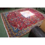 Large Persian Red Ground rug with central medallion and tassel ends 296cm by 240cm