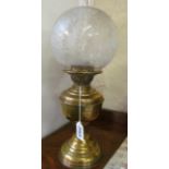 A brass oil lamp with etched glass shade