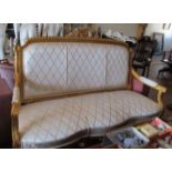 A gilt three seater Louis XVI style settee covered in gold on cream trellis pattern fabric
