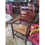 An oak ladder back rush seat chair and an elbow chair with tapestry seat