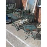 A green slatted metal garden table and four folding chairs