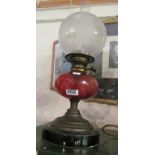 A Victorian oil lamp with etched glass shade and cranberry glass reservoir