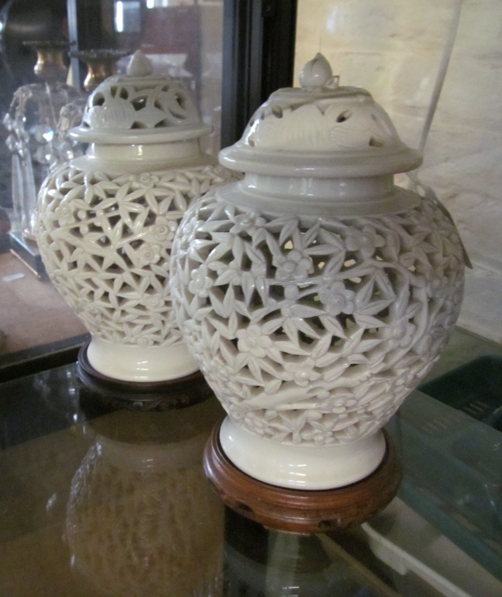 A pair of Oriental pierced lidded cream glazed vases flower and leaf design