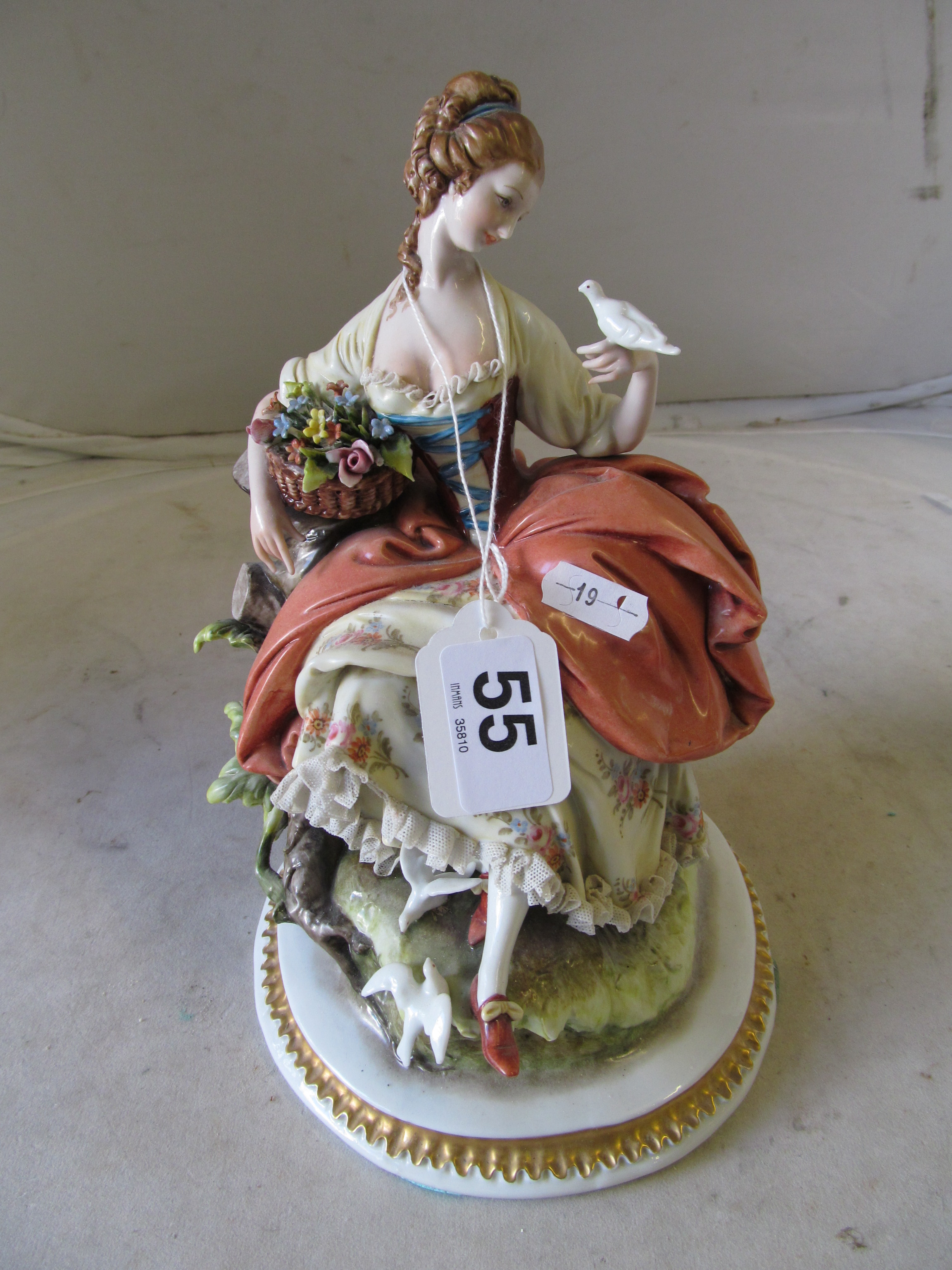 A Capodimonte figure lady with basket of flowers holding a dove