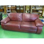 A dark red leather two seater settee
