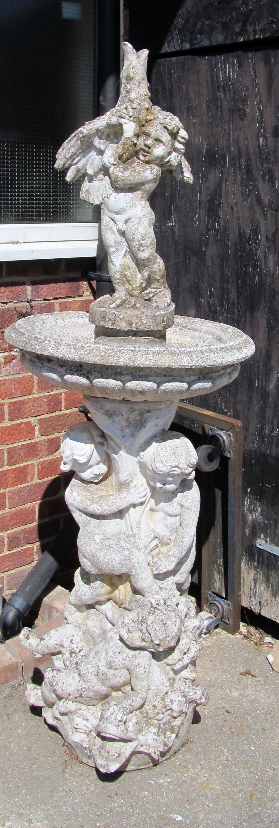 A large stoneware fountain with putti holding bird in bowl on a further column of putti on fish