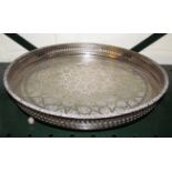 An eastern white metal circular tray with pierced border and engraved star design on claw feet.