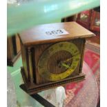 A small oak mantel clock with brass chapter ring