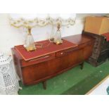 A retro teak bow fronted sideboard with three drawers, central dropfront and two side cabinets on