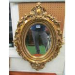 An ornate gilt frame oval mirror.