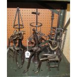 A set of three metal figures playing musical instruments and four metal stands