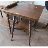 An Edwardian oak square topped table on bobbin turned supports on metal paw feet