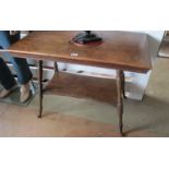 An Edwardian oak two tier table on turned supports on scroll metal feet