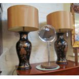 A pair of black and gilt floral lamps with gold coloured shades