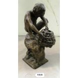 A modern bronze figure naked boy crouching on rock with octopus in basket