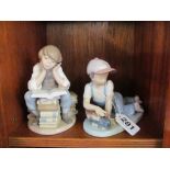 A Lladro boy playing with train and a Lladro boy reading a book with bird