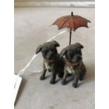 An Austrian cold-painted group of two pugs seated under umbrella