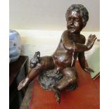 A large bronze figure cherub scared of a frog seated on his knee
