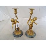 A pair of gilt metal candlesticks cherubs on marble bases