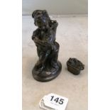 A bronze figure boy leaning against a tree stump with basket of grapes