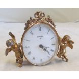 A small Swiza alarm clock with bow cresting and supported by cherubs