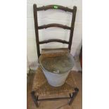 A galvanized metal bucket and ladder back chair