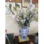 A blue and white vase with display of artificial flowers