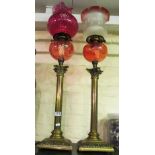 Two brass column oil lamps with glass shades