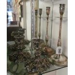 A pair of tall plated candlesticks and a pair of squat ornate candlesticks