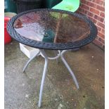 A glass topped and wicker effect circular garden table and three chairs