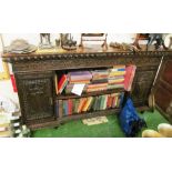 A carved narrow oak wall unit, two side doors and open shelves to centre