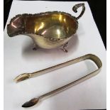 A silver shaped edge sauce boat and a pair of silver sugar tongs