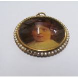 A gold coloured pendant with portrait of young girl with seed pearl surround the reverse with hinged
