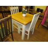 A fold top lightwood and cream kitchen table and two chairs