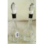 A pair of glass decanters with silver collars