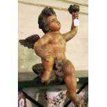 A large painted model of a cherub seated on a shell holding a torch