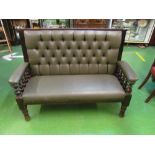 A mahogany bench seat with green leatherette button back
