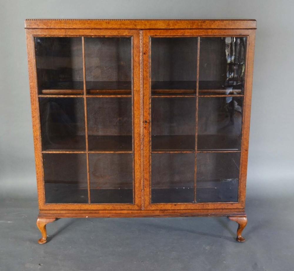 An Early 20th Century Burr Walnut Display Cabinet with two bar glazed doors enclosing shelves,