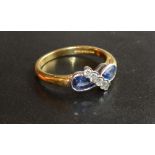 An 18 Carat Gold Sapphire and Diamond Ring set with two teardrop sapphires and with five crossover