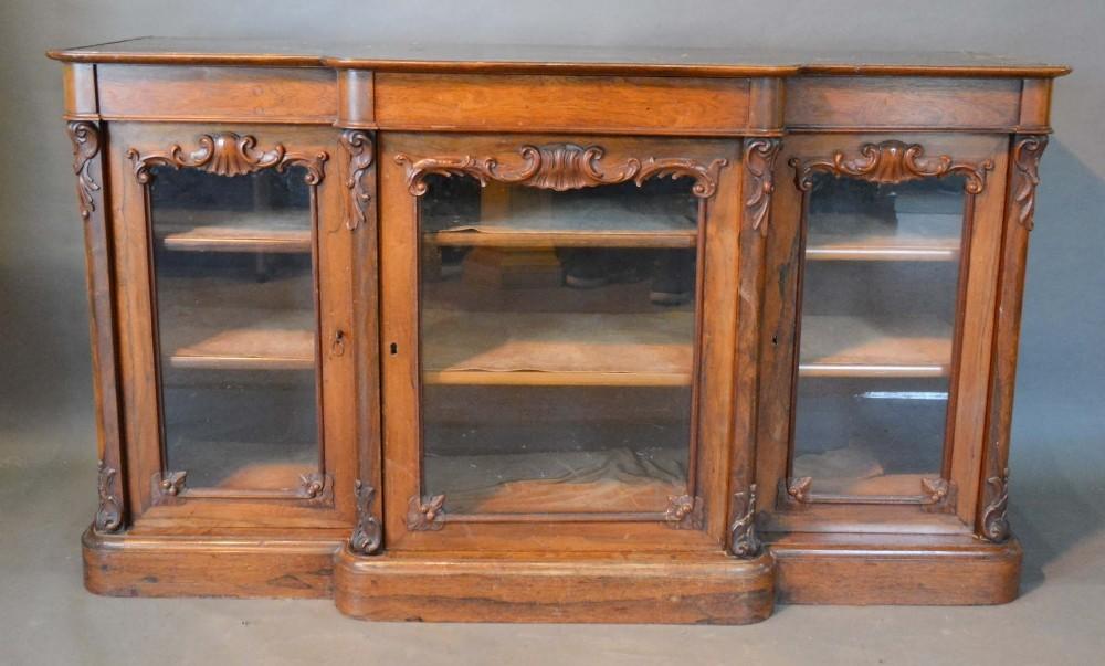 A Victorian Rosewood Breakfront Side Cabinet with three carved and glazed doors raised upon a