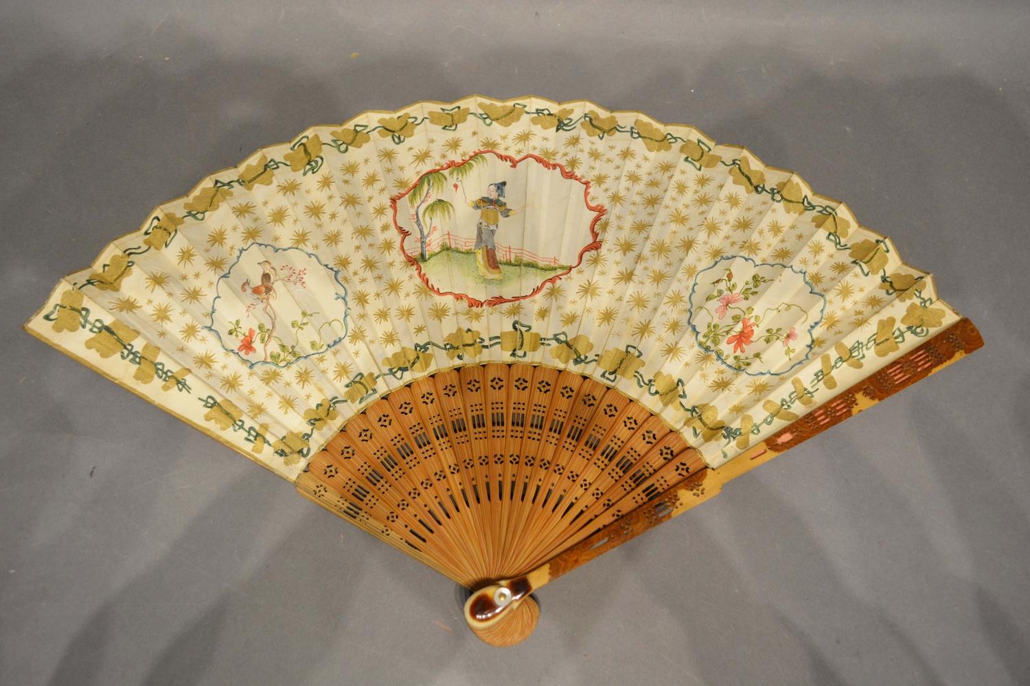 A 19th Century fan, hand painted with reserves within gilded decoration with finely pierced sticks