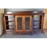 A Victorian Carved Oak Breakfront Bookcase, the moulded shaped top above two central brass grilles