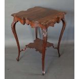 An Edwardian Mahogany Two Tier Occasional Table with a shaped moulded top raised upon carved