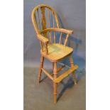 An Elm Windsor Style High Chair with a pierced splat and spindle back above a panel seat raised upon