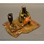 An Austrian Cold Painted Bronze Model in the form of an Arab on a rug with various implements, 10
