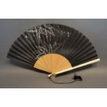 A Black Silk Leafed Fan, hand painted with dragonflies amongst foliage with bamboo sticks and