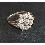 A Yellow Metal Diamond Cluster Ring with seven diamonds and small corner diamonds within a pierced